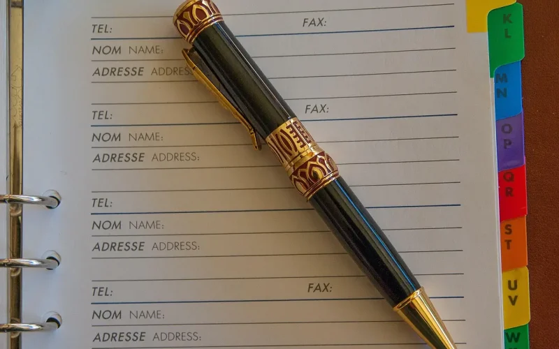 Pen resting on an open appointment book with labeled tabs, illustrating the concept of organized lead capture and scheduling for 24/7 client engagement.