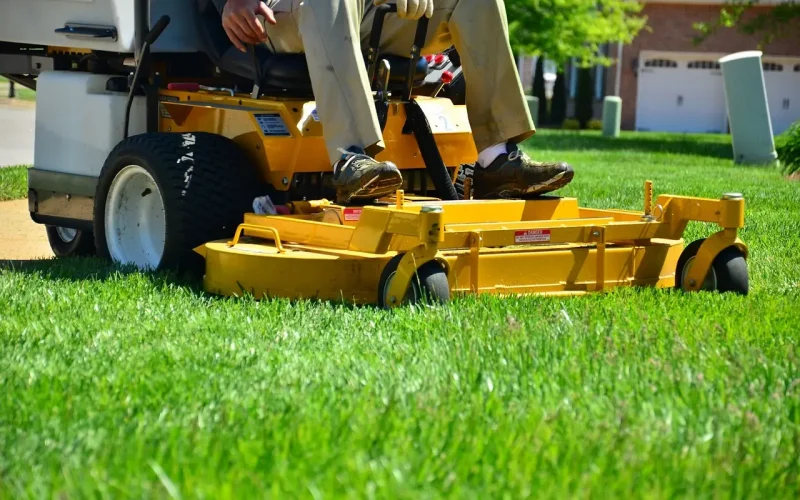 Person operating a riding lawn mower on lush green grass, demonstrating landscaping services and equipment relevant to lead generation for landscaping businesses.